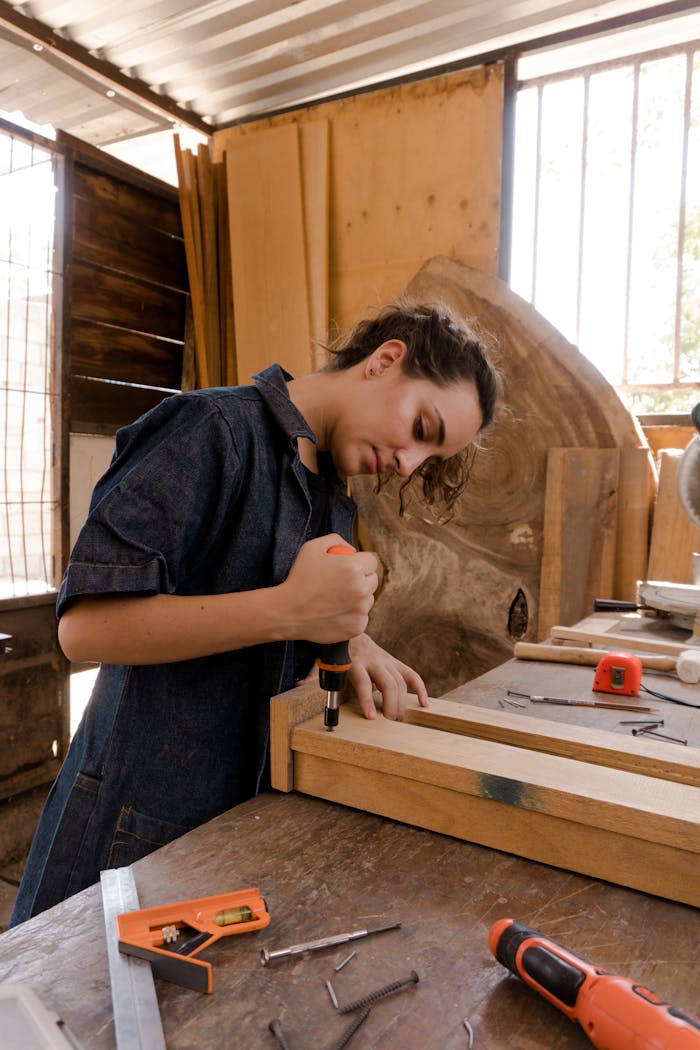 A skilled female carpenter using tools in a sunlit workshop, wearing coveralls and crafting a wooden piece.
